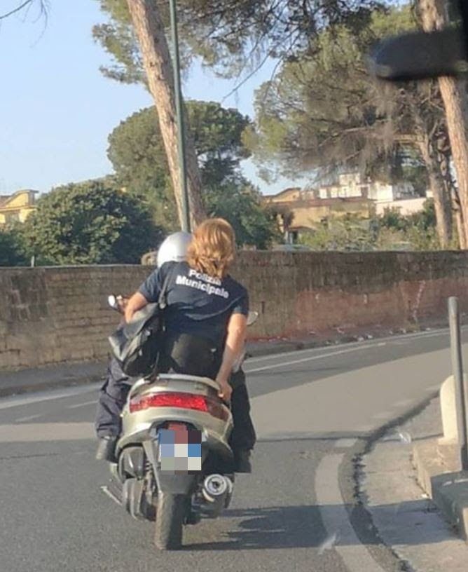 Agente della polizia municipale in scooter senza casco per le vie di Napoli