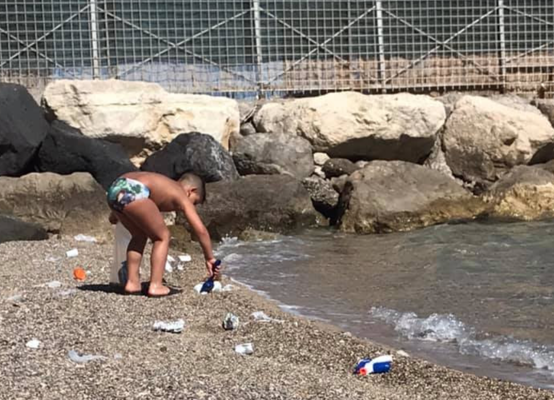 Castellammare, un bambino ripulisce una spiaggia dai rifiuti e dalle cicche lasciate dagli adulti