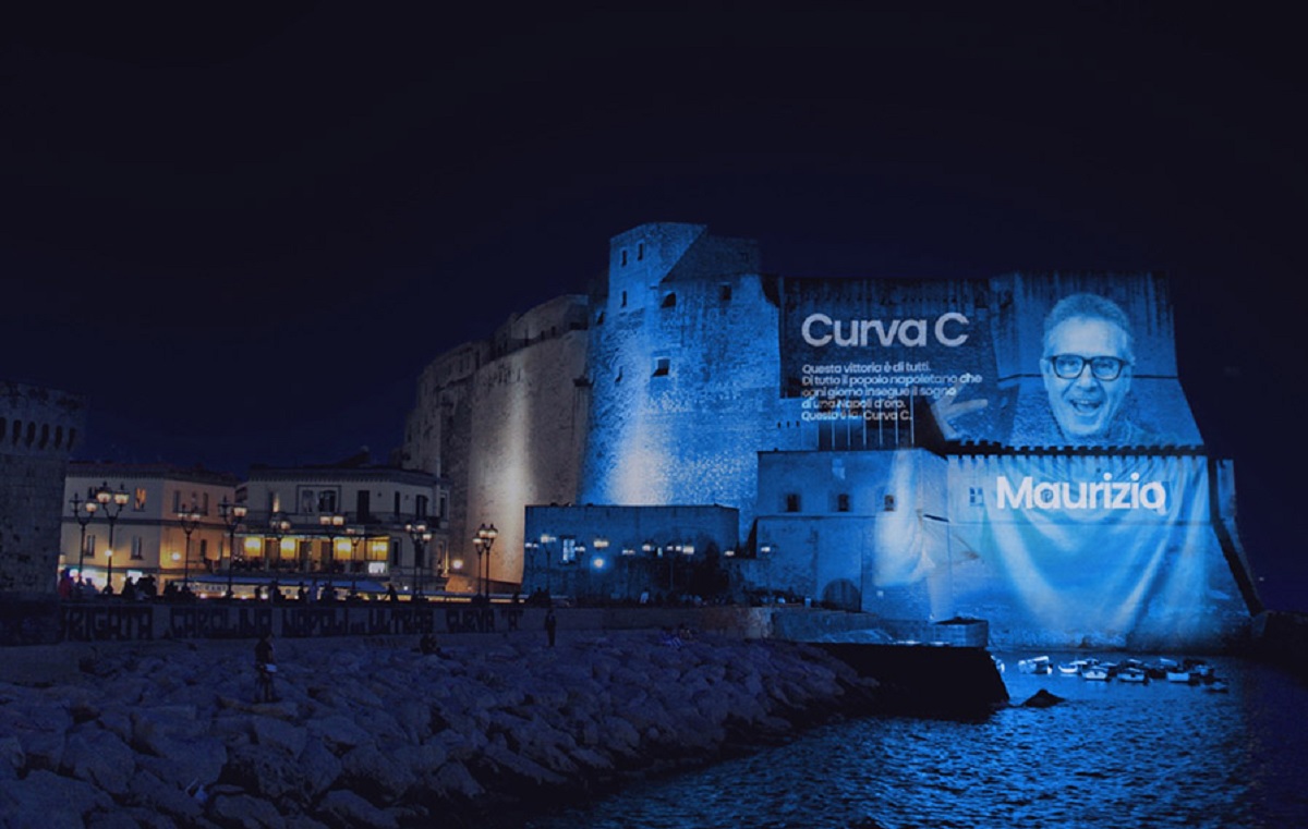 I volti di 200 tifosi del Napoli proiettati su Castel dell’Ovo: è “Curva C”, omaggio per lo scudetto